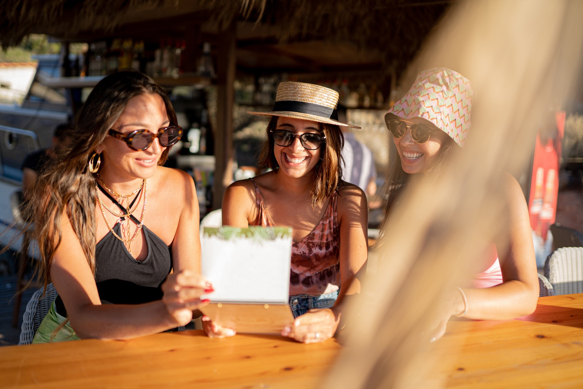 Girls having fun cheering with cocktails at bar on the beach