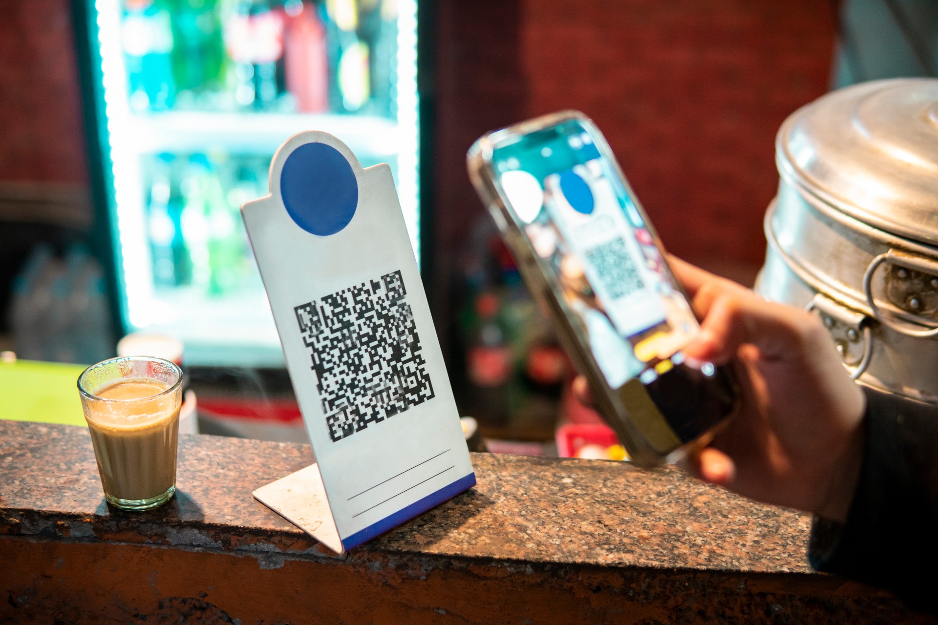 Close-up of customer hand scanning QR code with a smartphone for online payment.