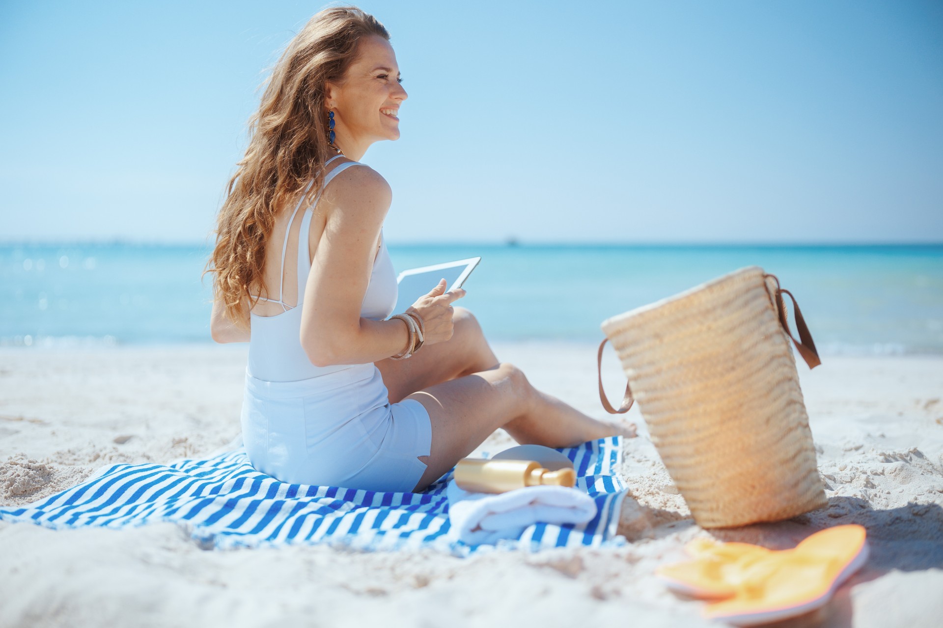 happy stylish female on beach using applications on tablet PC